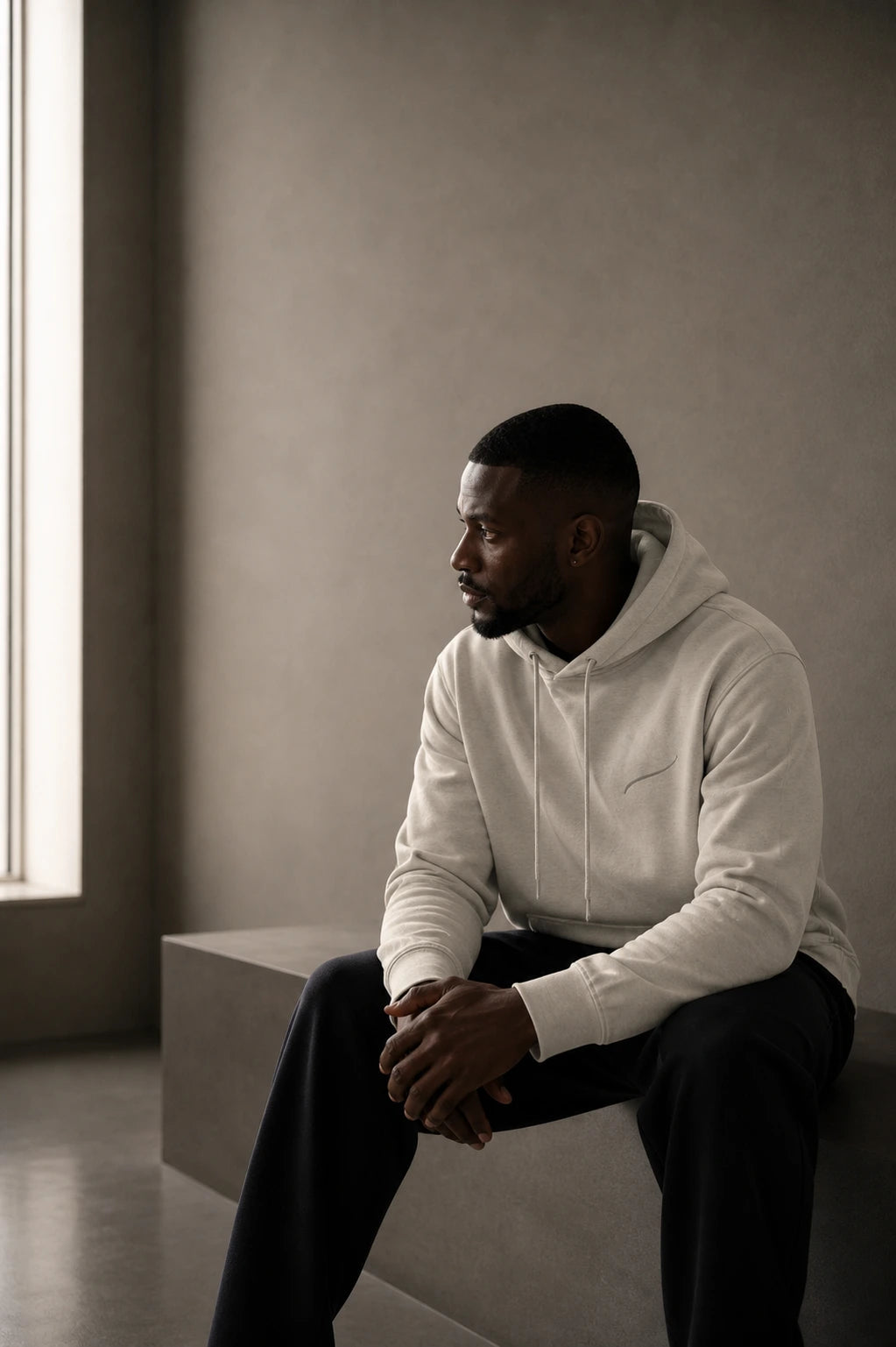 Editorial portrait featuring the BRTLS Core Hoodie Bone in a calm minimalist setting