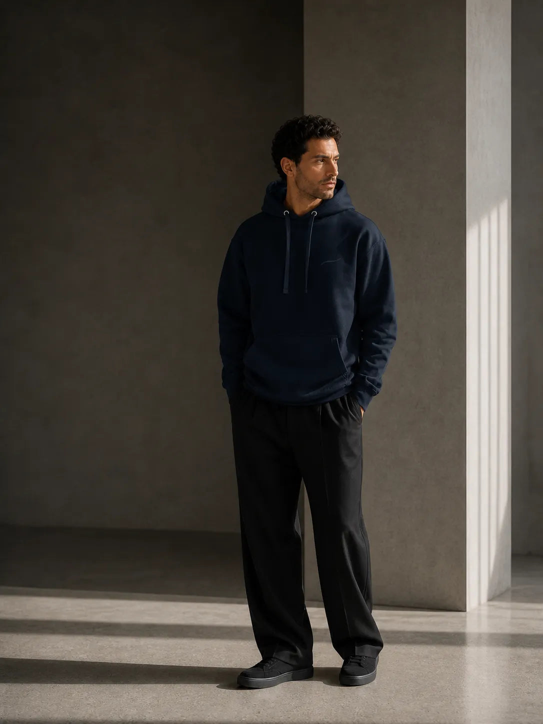 Man wearing the BRTLS Core Navy Hoodie in a minimalist architectural setting, representing modern fatherhood and intentional living