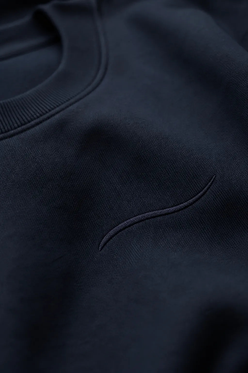 Close-up of tonal BRTLS signature embroidery on the Core Sweatshirt Navy, highlighting premium fabric texture and craftsmanship.