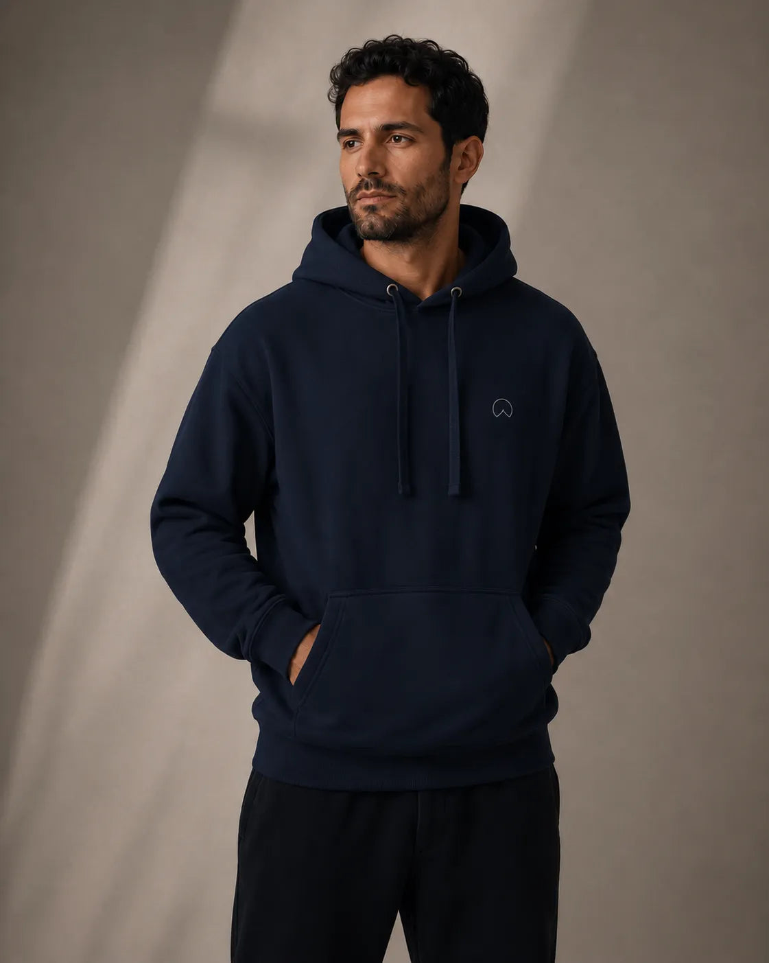 Modern man wearing the BRTLS Navy Presence Hoodie in a relaxed editorial studio portrait with heavyweight premium fit and minimalist design details.