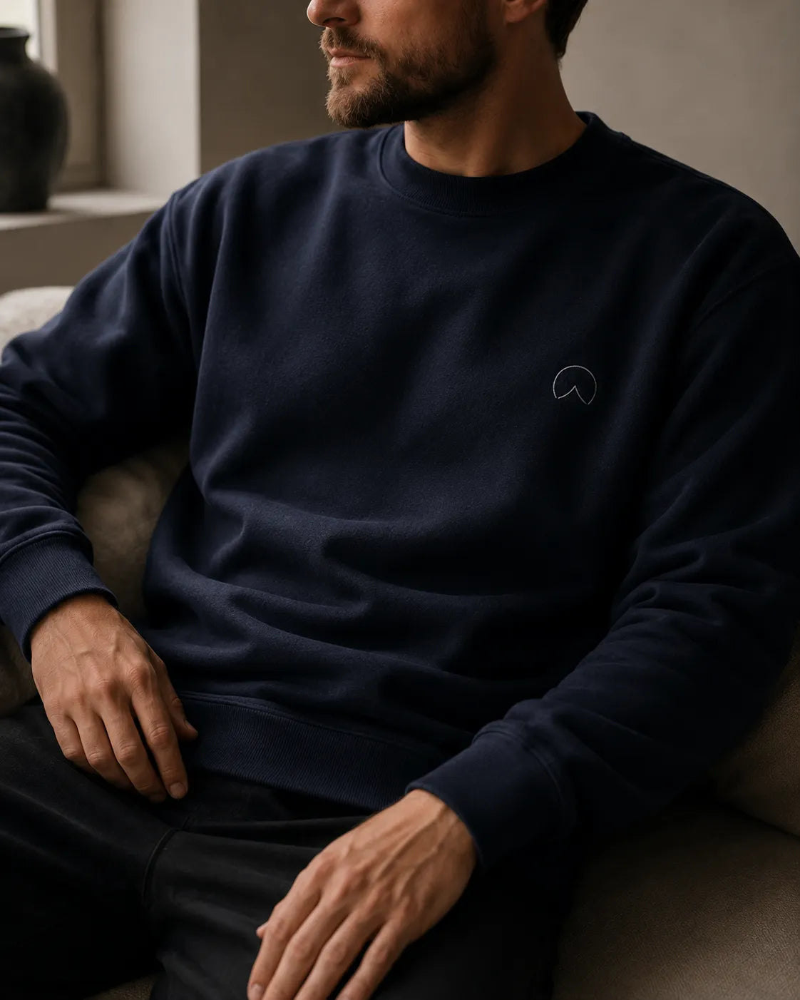 Close-up lifestyle detail of the BRTLS Own Your Presence Navy Sweatshirt showing premium cotton texture, relaxed fit and soft heavyweight fabric in a minimalist interior.