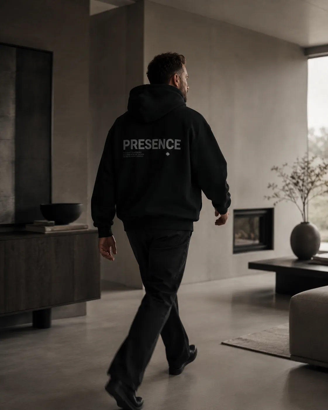 Editorial lifestyle image of The Presence Hoodie Black by BRTLS styled in a refined modern interior with understated movement
