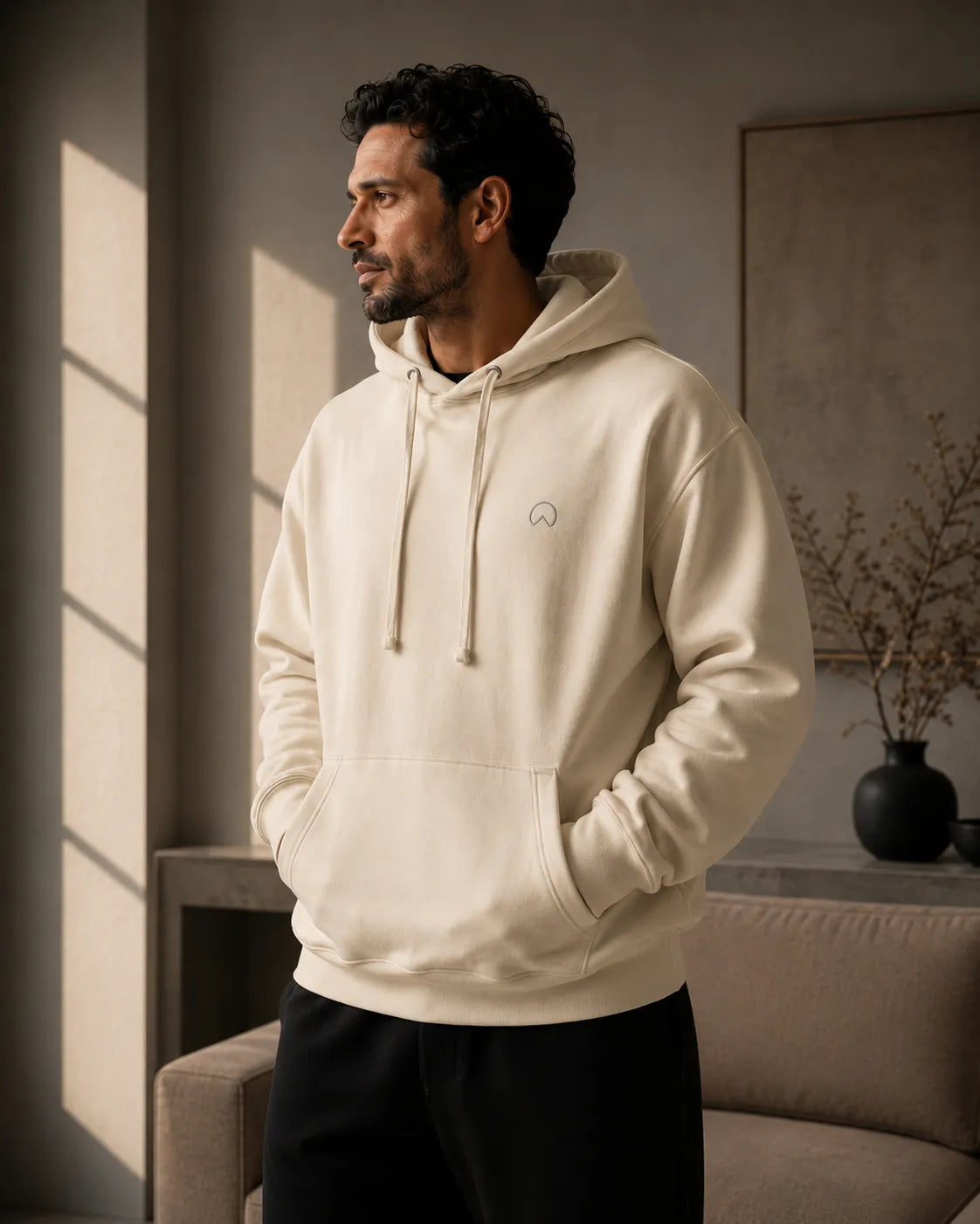 BRTLS Bone Presence Hoodie worn in a warm minimalist interior with relaxed oversized fit, heavyweight premium fabric and soft editorial lighting.