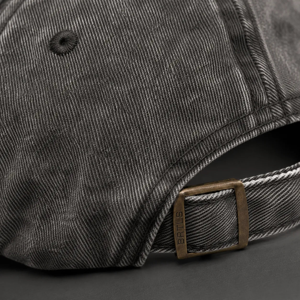 Close-up detail of the antique brass buckle and premium cotton twill on the BRTLS Charcoal Grey Presence Vintage Cap