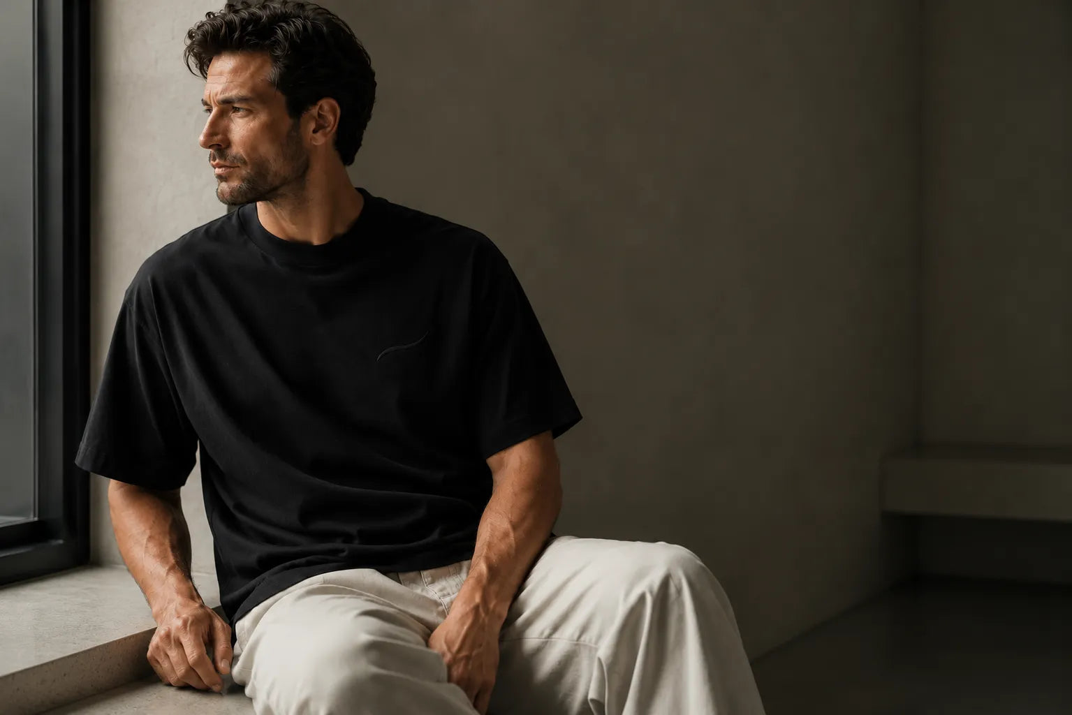 Man wearing the BRTLS Core Black Tee in a minimalist architectural setting, representing consistency, simplicity and modern fatherhood.
