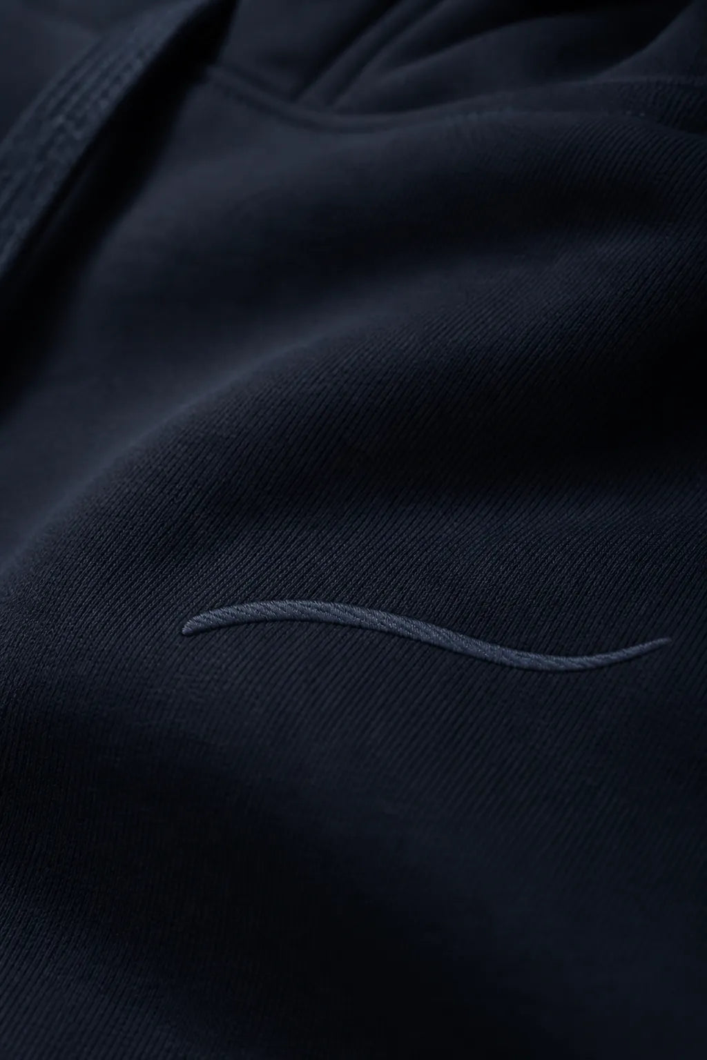 Close-up of the tonal BRTLS signature embroidery on the Core Navy Hoodie