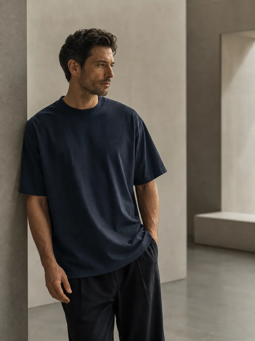 Man wearing the BRTLS Core Tee Navy Blazer in a minimalist architectural interior, showcasing refined modern fatherhood style and premium heavyweight cotton construction.