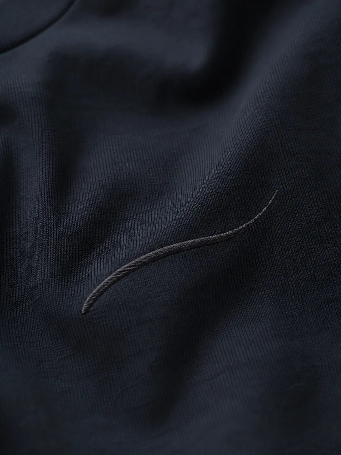 Close-up of the tonal embroidered BRTLS signature mark on the Core Tee Navy Blazer, highlighting premium craftsmanship and understated design.