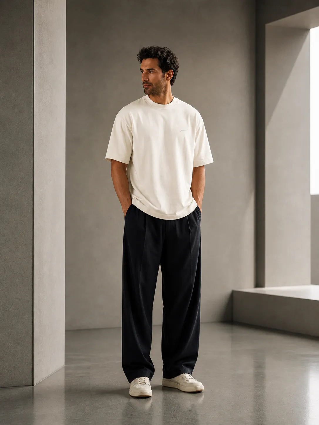 Man wearing the BRTLS Core Tee Vintage White in a minimalist architectural interior, showcasing timeless style and premium heavyweight cotton construction.