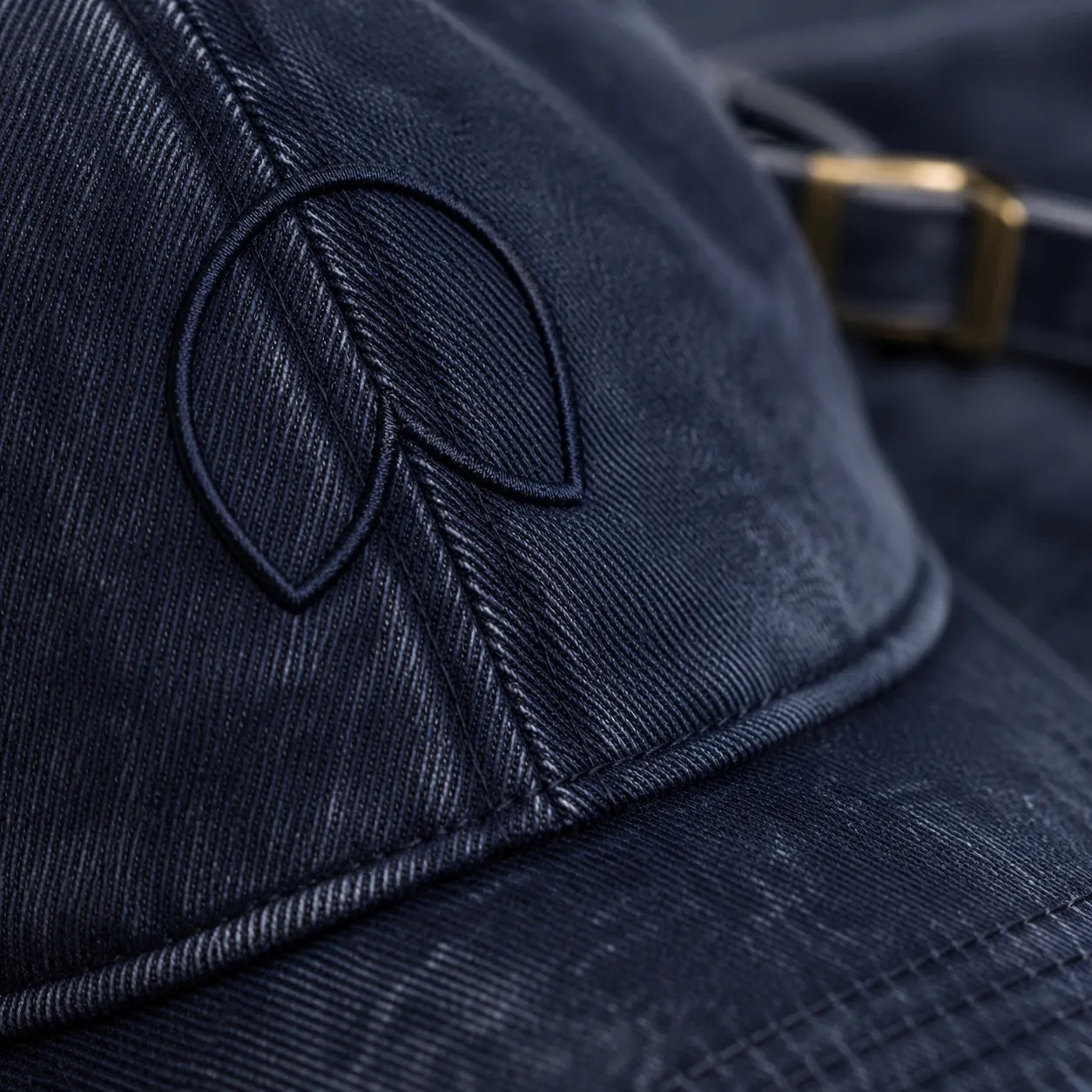 Close-up detail of the tonal embroidered BRTLS signature mark on the Navy Presence Vintage Cap