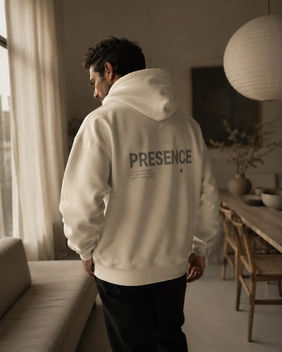 Editorial lifestyle image of the bone BRTLS Presence Hoodie in a refined minimalist interior setting