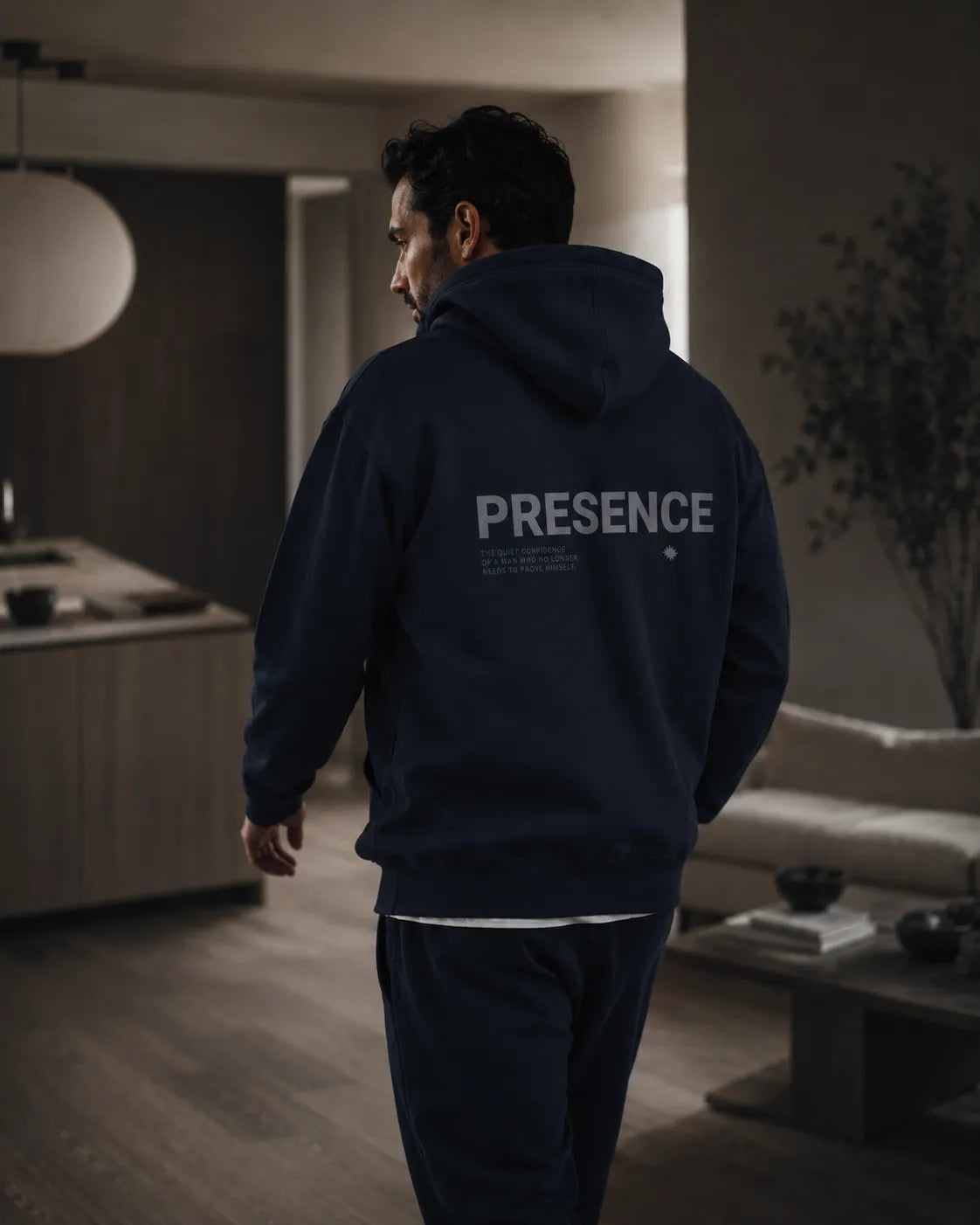 Lifestyle afbeelding van man in navy BRTLS Presence hoodie wandelend door modern minimalistisch interieur met quiet luxury uitstraling
