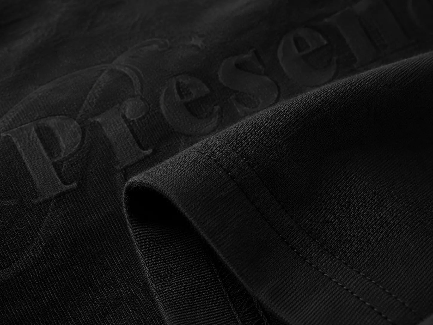Close-up detail of the BRTLS Refined Presence Tee Black showing heavyweight cotton texture and tonal print